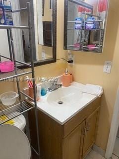 half bathroom with vanity, toilet, and tile patterned flooring