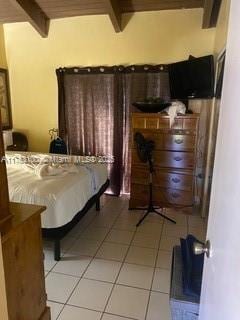 bedroom with beam ceiling and light tile patterned floors