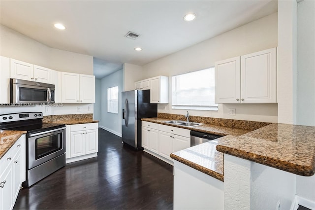 kitchen featuring white cabinetry, a peninsula, stainless steel appliances, and a sink