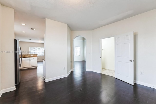 unfurnished room with dark wood finished floors, recessed lighting, baseboards, and arched walkways