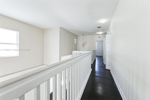 corridor with dark wood finished floors, an upstairs landing, baseboards, and visible vents