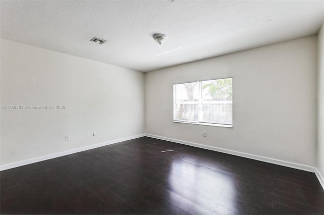 empty room with visible vents, baseboards, and dark wood-style flooring