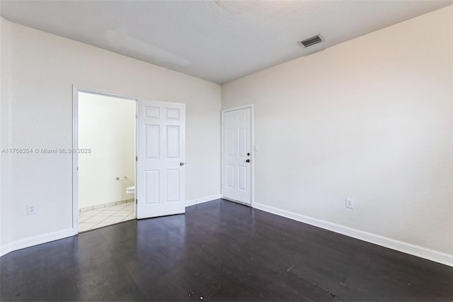 unfurnished room featuring visible vents, baseboards, and wood finished floors