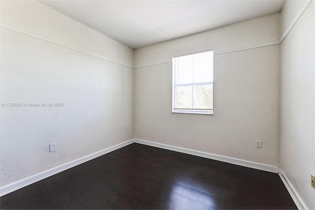 unfurnished room with baseboards and dark wood-style flooring