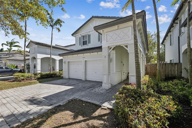 view of front of house featuring stucco siding, an attached garage, decorative driveway, and fence