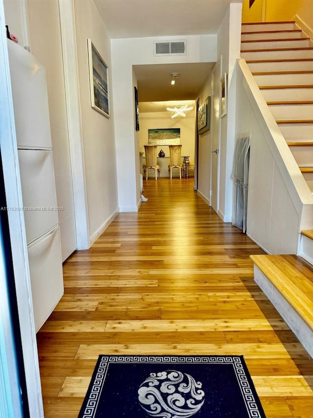 hall featuring visible vents, stairway, light wood-type flooring, and baseboards