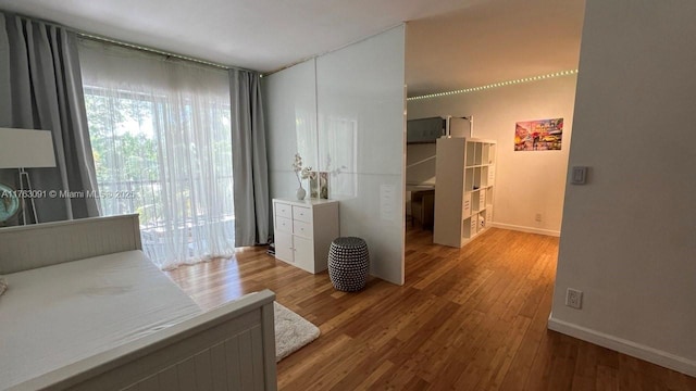 bedroom featuring access to exterior, baseboards, and wood finished floors