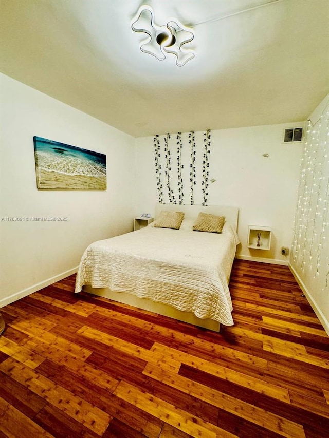 bedroom featuring wood finished floors, visible vents, and baseboards