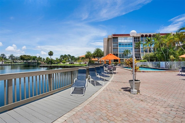 view of dock featuring a community pool, a patio area, and a water view