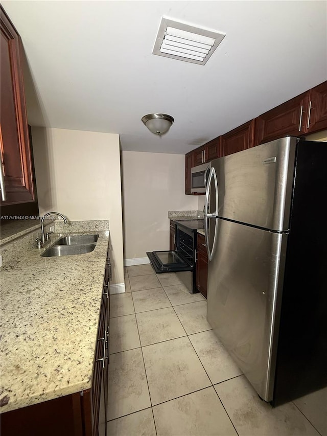 kitchen featuring visible vents, a sink, appliances with stainless steel finishes, light tile patterned floors, and baseboards