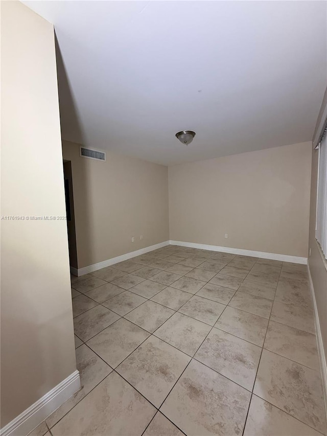 empty room with light tile patterned floors, baseboards, and visible vents