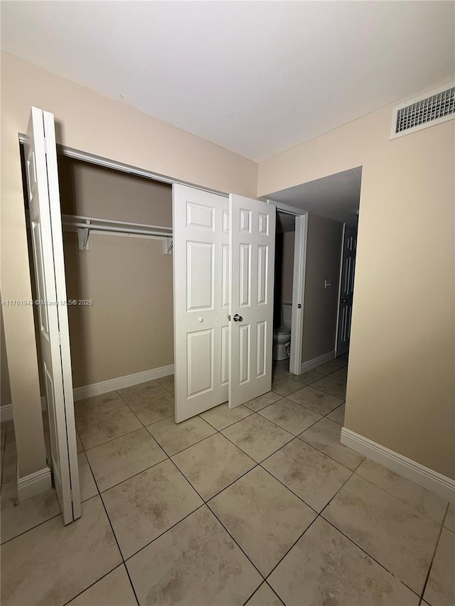 unfurnished bedroom with light tile patterned floors, visible vents, baseboards, and a closet