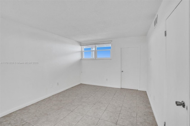 spare room featuring visible vents, a textured ceiling, and baseboards