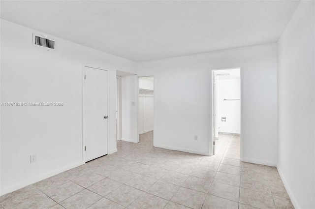 empty room with light tile patterned floors, visible vents, and baseboards