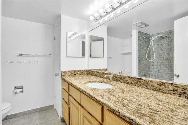 bathroom with toilet, tiled shower, tile patterned flooring, baseboards, and vanity