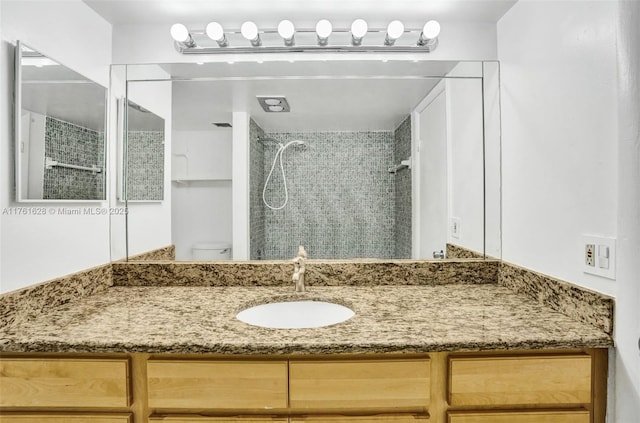 bathroom featuring toilet, vanity, and a tile shower