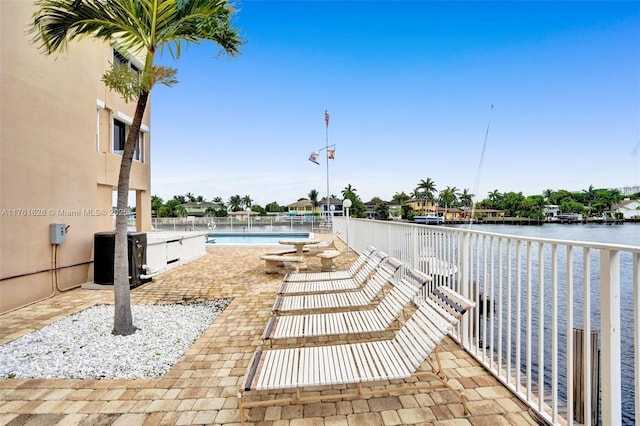 view of patio / terrace with a community pool, cooling unit, and a water view