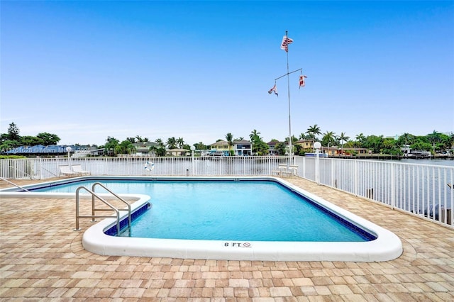 community pool with a patio area, a water view, and fence