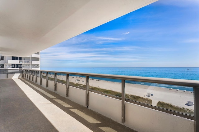 balcony featuring a view of the beach and a water view