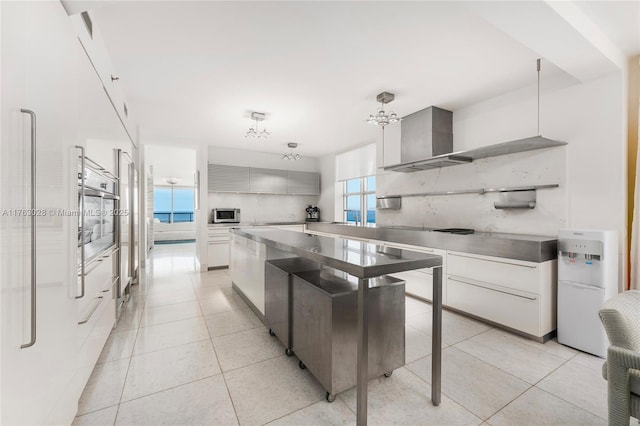 kitchen featuring wall chimney range hood, light tile patterned floors, modern cabinets, and tasteful backsplash