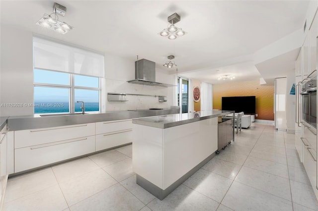 kitchen with light tile patterned flooring, oven, modern cabinets, and wall chimney exhaust hood