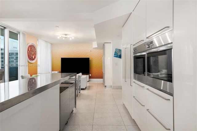 kitchen with oven, open floor plan, light tile patterned floors, white cabinetry, and modern cabinets