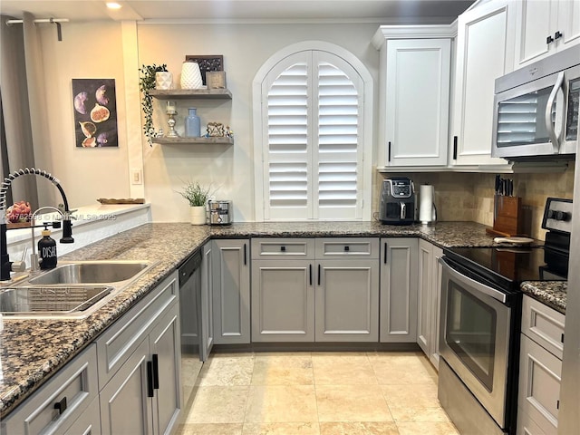 kitchen with a sink, decorative backsplash, dark stone countertops, stainless steel appliances, and open shelves