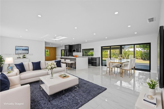 living area with recessed lighting, visible vents, and marble finish floor