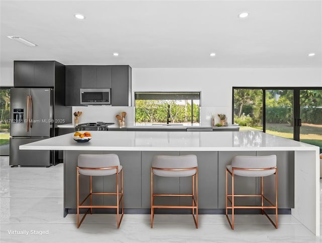 kitchen with a breakfast bar, light countertops, appliances with stainless steel finishes, modern cabinets, and a sink