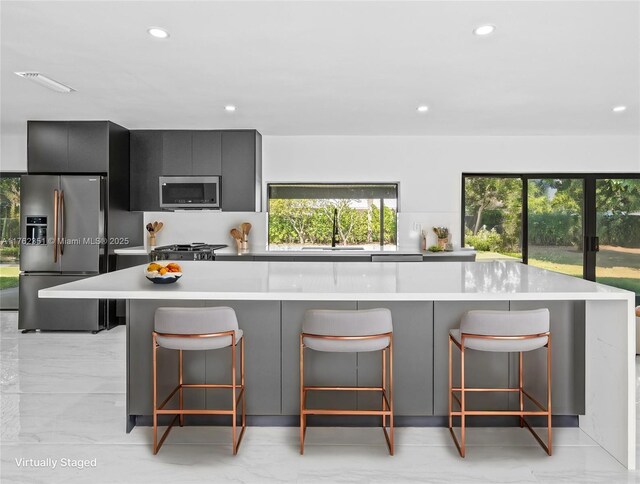 kitchen with a breakfast bar, light countertops, appliances with stainless steel finishes, modern cabinets, and a sink