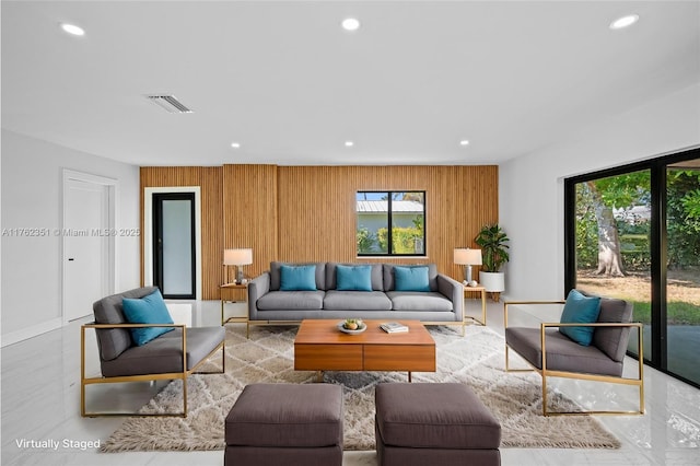 living room with recessed lighting, visible vents, and wood walls