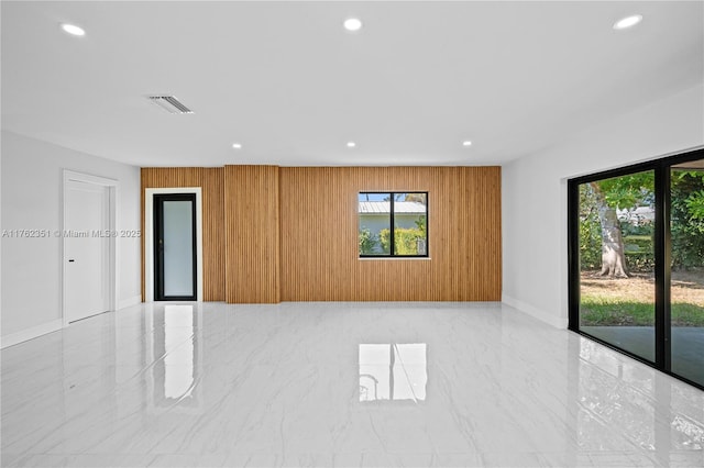 empty room featuring visible vents, recessed lighting, marble finish floor, and wood walls