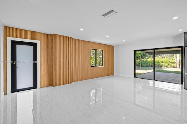 empty room featuring visible vents, recessed lighting, marble finish floor, and wooden walls