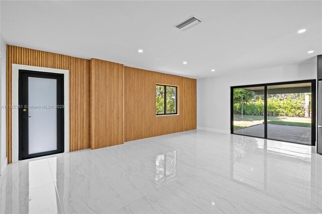 empty room featuring visible vents, recessed lighting, marble finish floor, and wooden walls