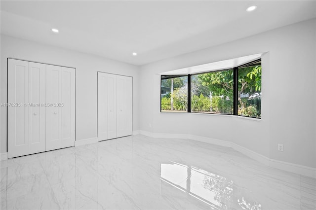 unfurnished bedroom with recessed lighting, baseboards, multiple closets, and marble finish floor