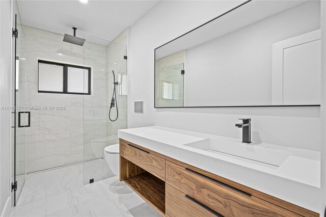 bathroom with vanity, toilet, marble finish floor, and a marble finish shower