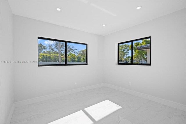 spare room featuring plenty of natural light, recessed lighting, and baseboards