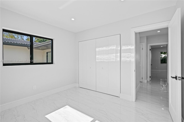 unfurnished bedroom with a closet, recessed lighting, baseboards, and marble finish floor