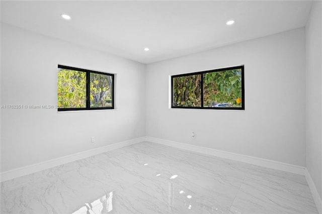 empty room featuring recessed lighting, baseboards, and marble finish floor