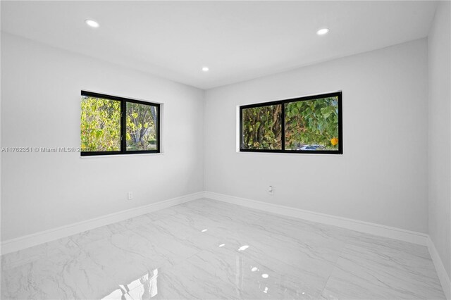 empty room featuring recessed lighting, baseboards, and marble finish floor