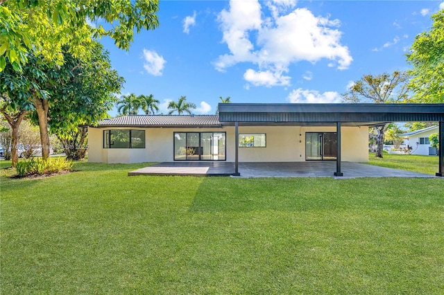 rear view of property featuring a patio, a yard, and stucco siding