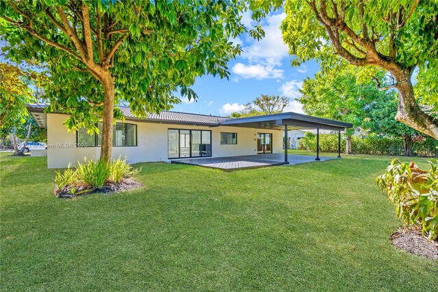 rear view of house featuring a lawn and stucco siding