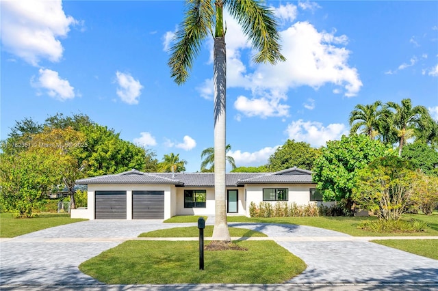 view of front of home with decorative driveway, a front yard, an attached garage, and stucco siding