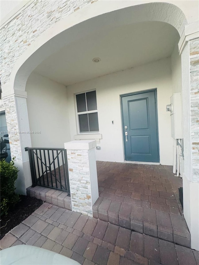 doorway to property with stucco siding and stone siding