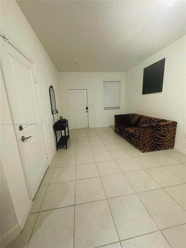 sitting room with light tile patterned floors, baseboards, and a textured ceiling