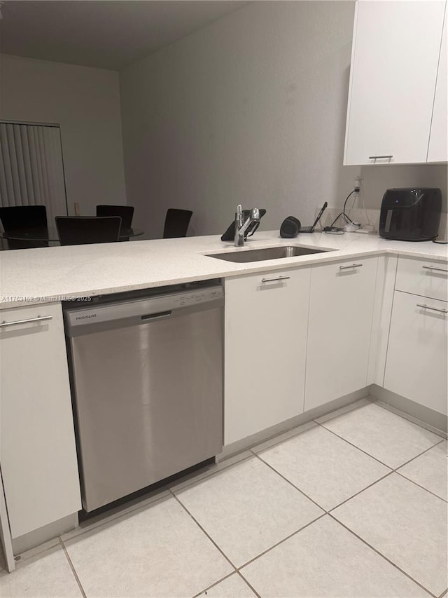 kitchen with a sink, stainless steel dishwasher, white cabinetry, a peninsula, and light tile patterned floors