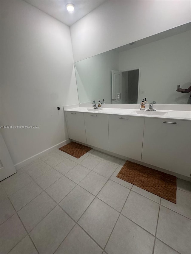 bathroom featuring tile patterned floors, double vanity, baseboards, and a sink