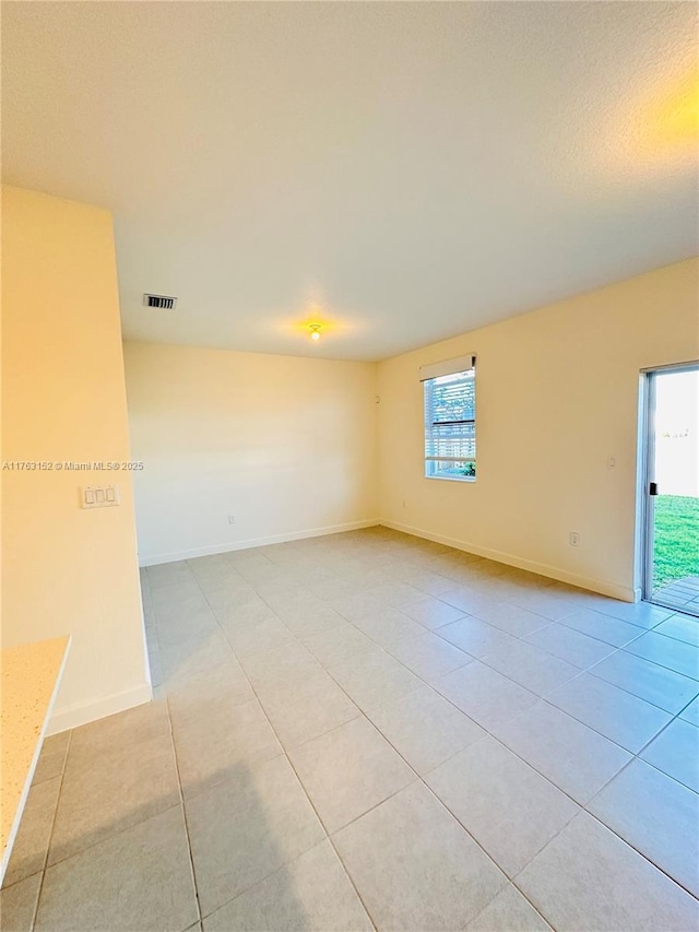 unfurnished room featuring light tile patterned flooring, visible vents, and baseboards