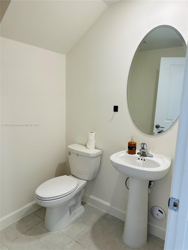 half bathroom with baseboards, toilet, tile patterned flooring, and vaulted ceiling