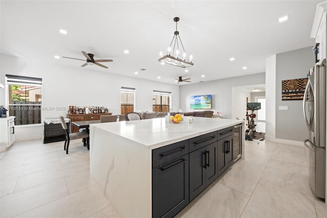 kitchen with a kitchen island, open floor plan, ceiling fan with notable chandelier, freestanding refrigerator, and white cabinets